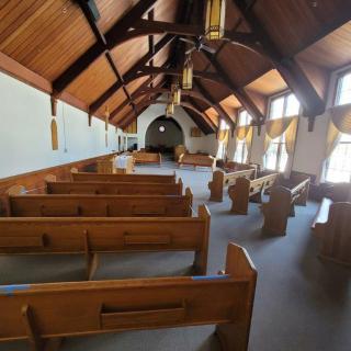 An empty chapel with wooden pews and a vaulted ceiling.