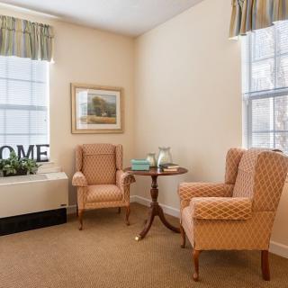 A cozy living room corner featuring two armchairs and a small table by the window.