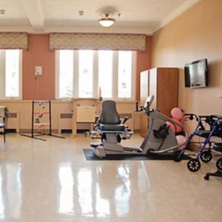 A well-lit rehabilitation room with various exercise equipment and chairs.
