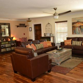 A cozy living room featuring leather sofas, wooden flooring, and warm decor.