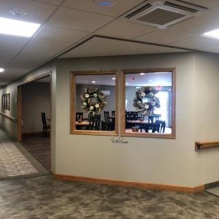 A hallway with windows showcasing a decorated dining area and ceiling lights.