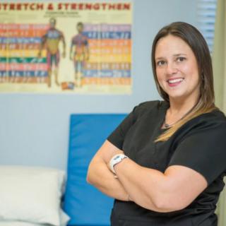 A healthcare professional standing confidently in a medical office with an exercise poster in the background.