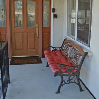 A porch with a wooden door and a bench with red cushions.