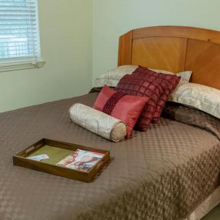 A neatly arranged bedroom with a wooden headboard, decorated with pillows and a tray on the bed.