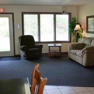 A cozy living room with a sofa, armchair, and large windows.