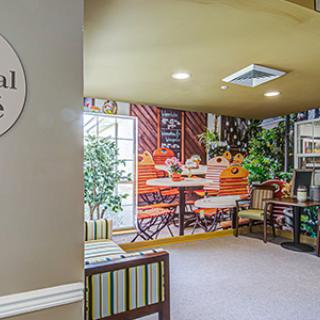 A cozy waiting area with a wall mural depicting an outdoor caf scene, complemented by comfortable seating and decorative plants.