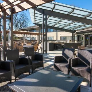 A stylish outdoor patio area featuring modern furniture under a pergola on a sunny day.