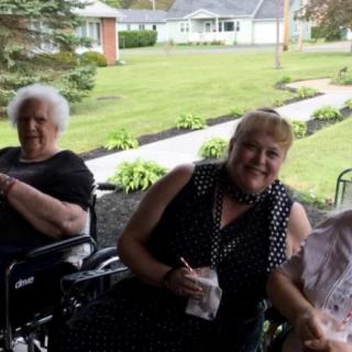 Three women enjoying time together outside on a lawn.