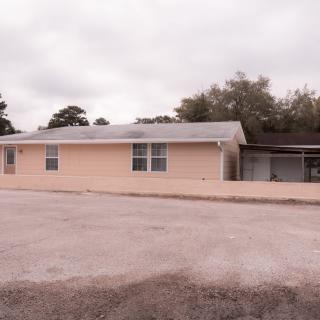 A one-story residential house with a driveway on a cloudy day.