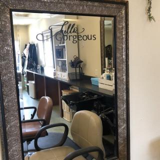 A salon interior featuring a large mirror and hairdressing chairs.