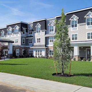 A modern residential building with a well-maintained lawn and blue skies.