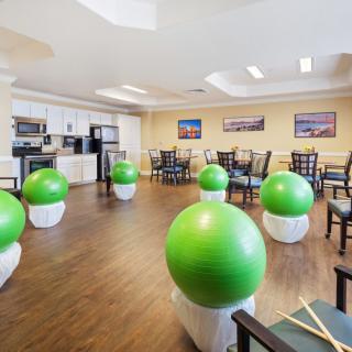 A fitness room equipped with green exercise balls and drumsticks, featuring a seating area and wooden flooring.