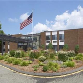 A school building with an American flag and landscaped entrance.