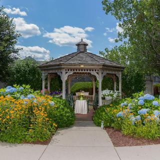 A charming gazebo surrounded by vibrant flowers on a sunny day.