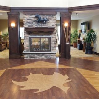 A cozy lobby featuring a stone fireplace, wooden flooring, and decorative elements that create a warm atmosphere.