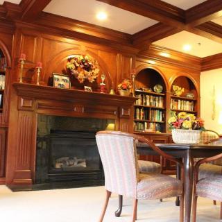 A cozy living room with elegant wood paneling, featuring a fireplace and built-in bookshelves.