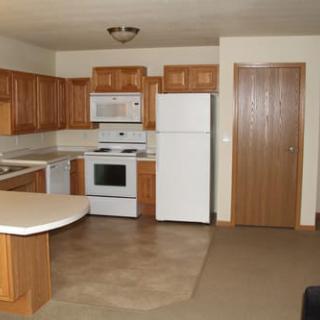 A kitchen with wooden cabinets, featuring a refrigerator, microwave, and oven.