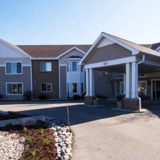 A modern hotel entrance with a covered driveway and landscaped surroundings.