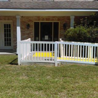 A house with a yellow ramp and white railings leading to the back patio.