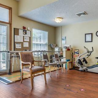 A rehabilitation room with exercise equipment and seating.