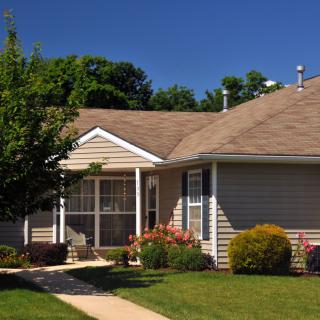 A suburban house with a well-maintained garden and clear blue sky.