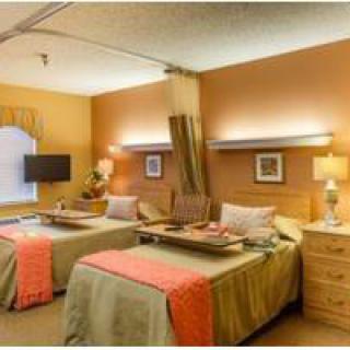 A hospital room with two comfortable beds, each equipped with a lamp and a privacy curtain.