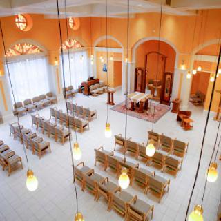 A spacious and elegantly designed interior of a church or gathering space, featuring rows of seating and warm lighting.