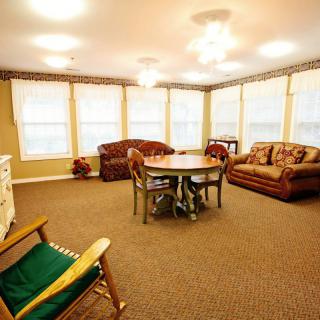 A cozy living room with multiple sofas, a round table, and large windows allowing ample natural light.