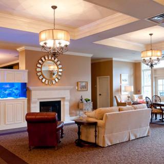A modern living room featuring a comfortable seating area with a sofa, a fireplace, elegant chandeliers, and a wall-mounted television.