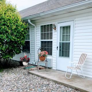 A cozy patio area with a door, windows, potted plants, and a chair.