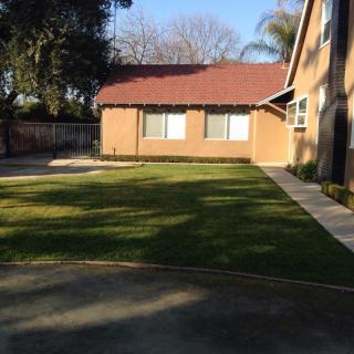 A spacious yard with a well-maintained lawn next to a brick house.