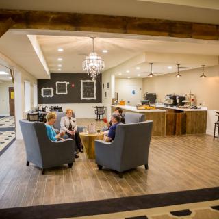 Three people sitting and conversing in a modern lobby area with stylish decor and ample lighting.