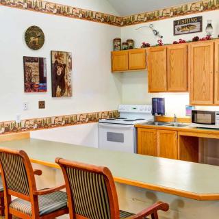 A cozy kitchen area with wooden cabinets, a stove, and a microwave, complemented by a counter with bar stools.