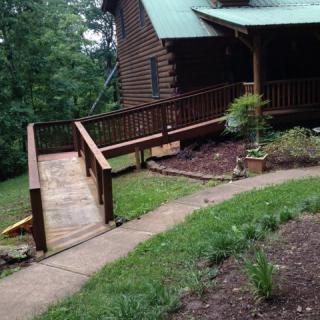 A cozy cabin with a wooden ramp leading to the porch, surrounded by a landscaped garden.