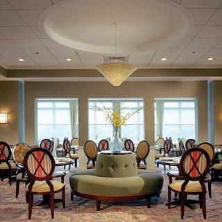 A well-lit dining room with elegant seating and a central chandelier.