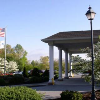 A building entrance with columns and an American flag, surrounded by landscaped greenery.