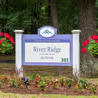 Entrance sign for River Ridge community, surrounded by flowers and greenery.