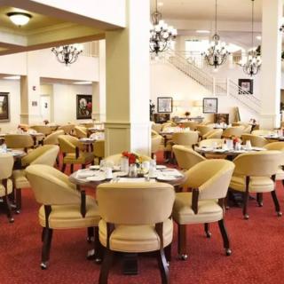 Elegant dining area featuring arranged tables and upholstered chairs with chandeliers hanging from the ceiling.