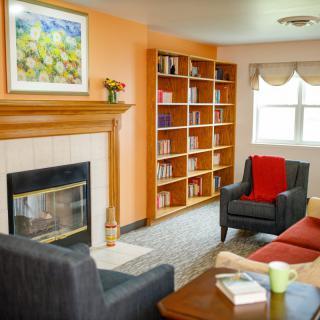 A cozy living room with a fireplace, bookshelves, and comfortable seating.