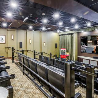 A luxury home theater room with tiered seating and a projector screen.