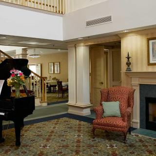 A cozy living room with a grand piano and a comfortable armchair by the fireplace.