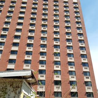 A tall brick building with numerous windows under a clear blue sky.