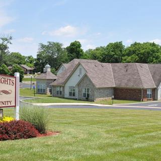 A residential building with a landscaped lawn and a sign indicating property name.