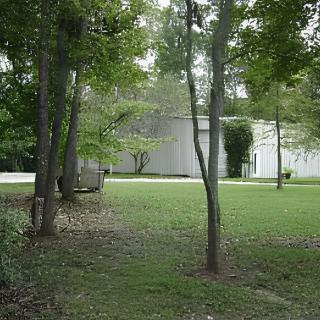 A modern house surrounded by trees and a grassy yard.