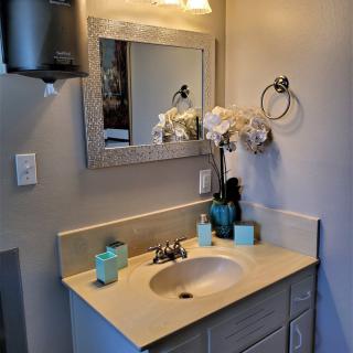 A neatly organized bathroom with a sink, mirror, and decorative elements.