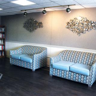 A modern waiting room with patterned sofas and decorative wall art.