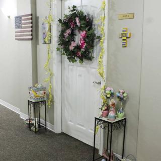 A decorated doorway with a wreath and flowers in a hallway.