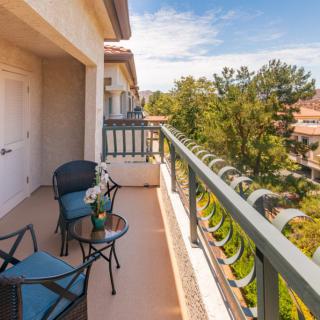 A cozy balcony with seating overlooking a lush residential area.