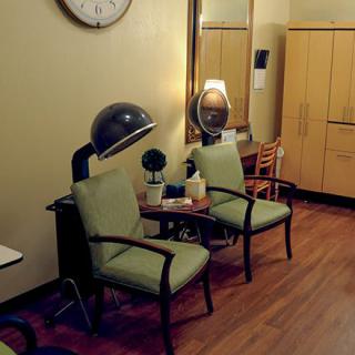 A vintage salon interior featuring retro chairs, hairdryers, and a large mirror.