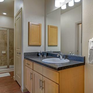 A modern bathroom interior featuring a vanity with a sink, mirror, and overhead lighting.